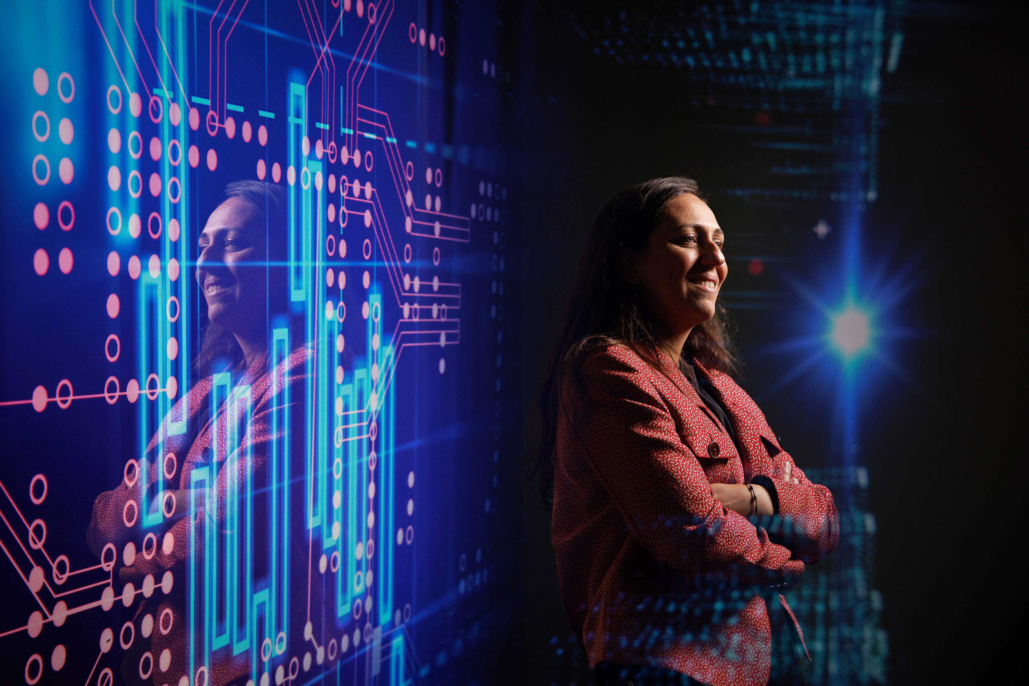 woman poses in dark room with abstract digital backdrop