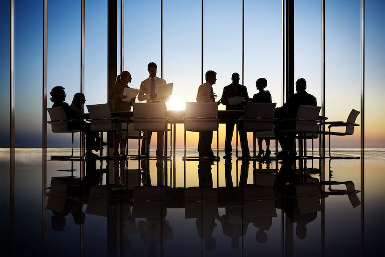 Silhouettes of professionals discussing in a conference room, engaged in a productive business meeting.