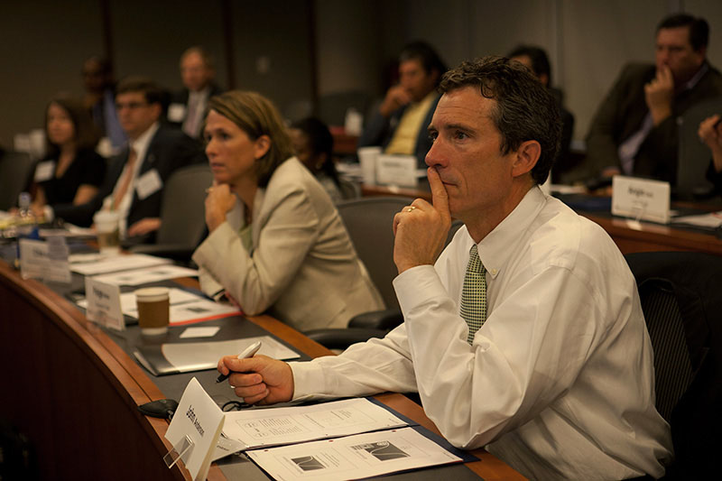 A man in a suit and tie takes notes during a Certified Financial Planner training course.