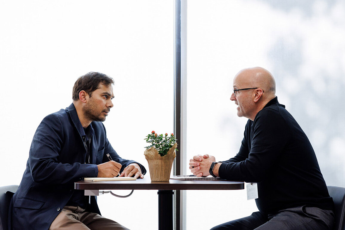 Two men having a conversation over a table. 