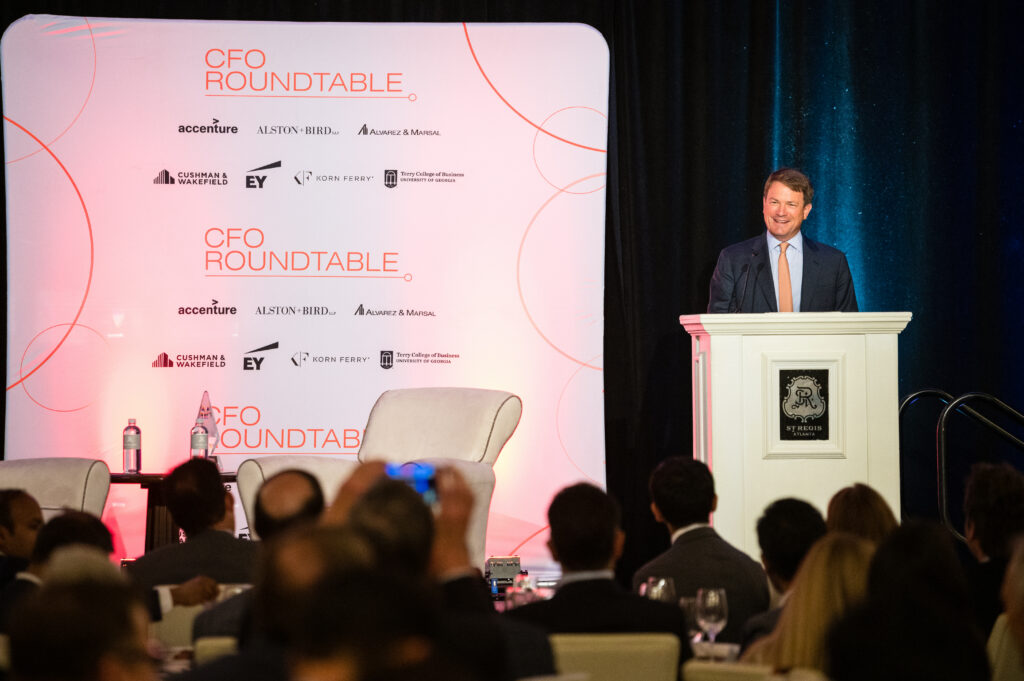 A man stands at a podium and talks to his audience during a CFO Roundtable event.