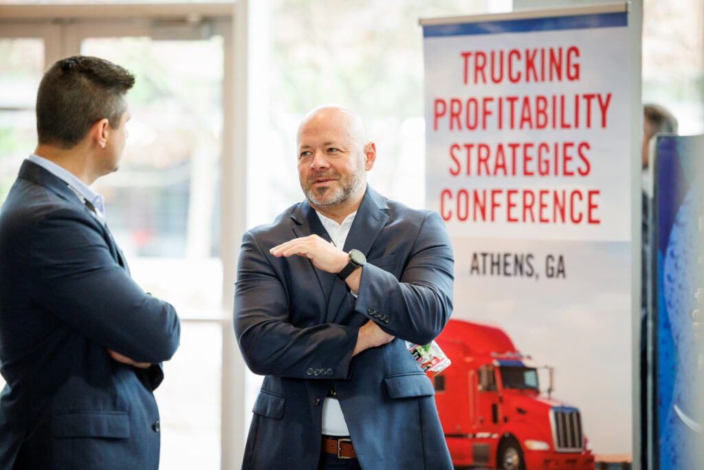 Two men talk to each other during a Trucking Profitability Strategies Conference.