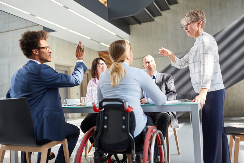 A woman in a wheelchair engaging in conversation with individuals during a meeting.