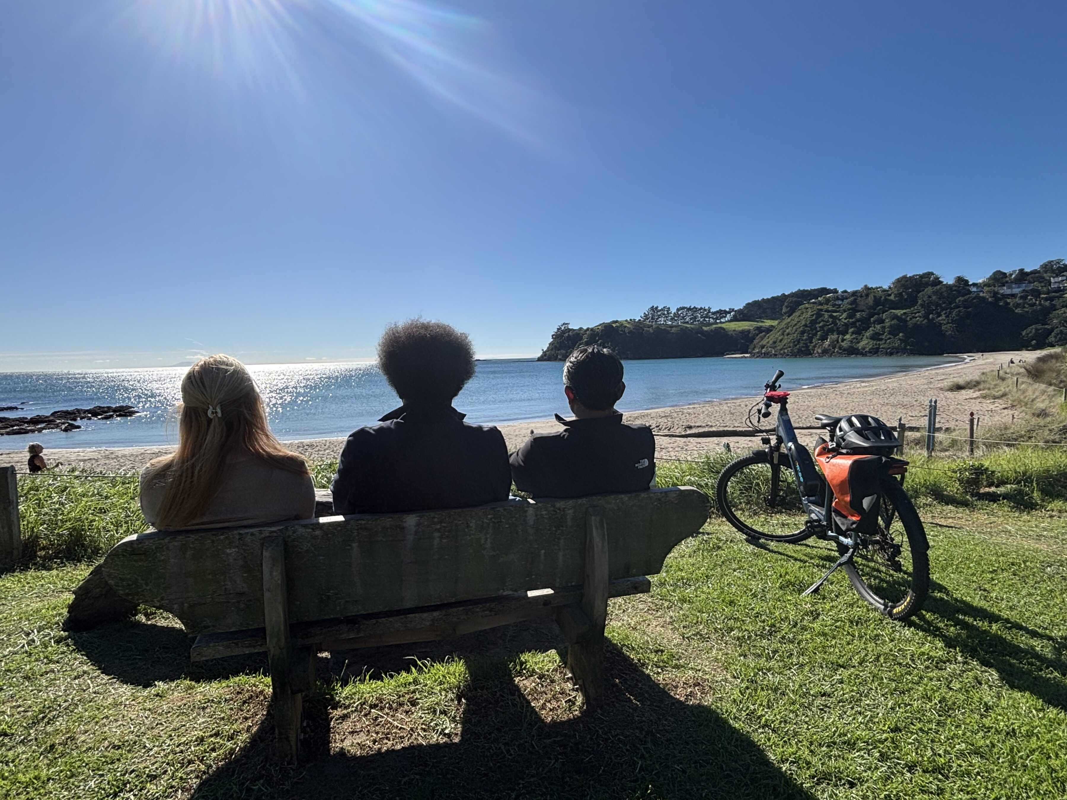 Terry College MBA students sit on a bench by a beach while looking at the ocean in New Zealand.