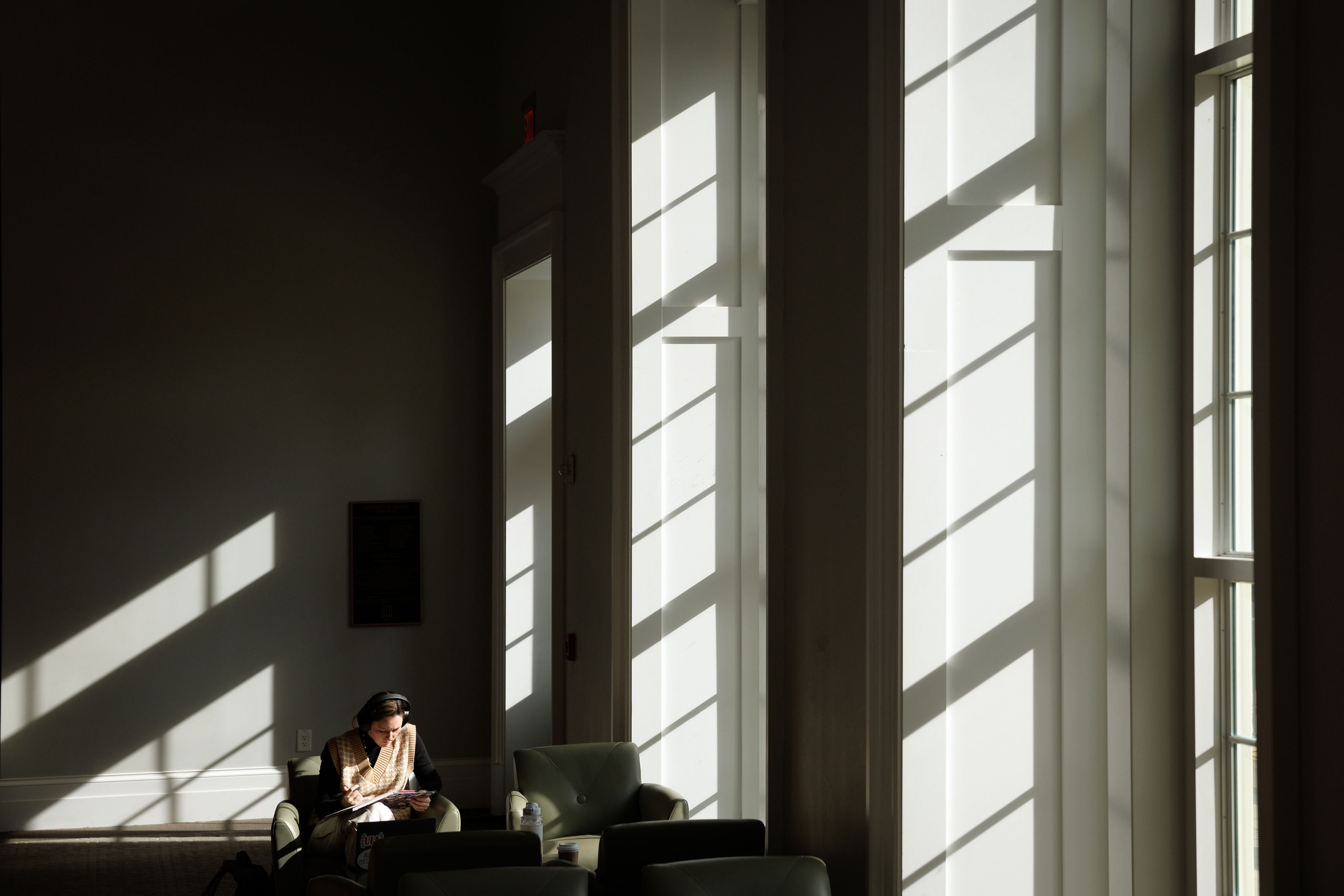 A Terry College student sitting on a couch reading in Casey Commons 