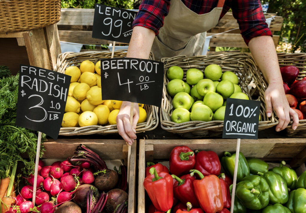 A produce aisle at the grocery store featuring vegetables and fruits, some of which are priced by pound and some priced by item. Research shows perception of grocery prices changes based on the size of the time and how the price is listed.