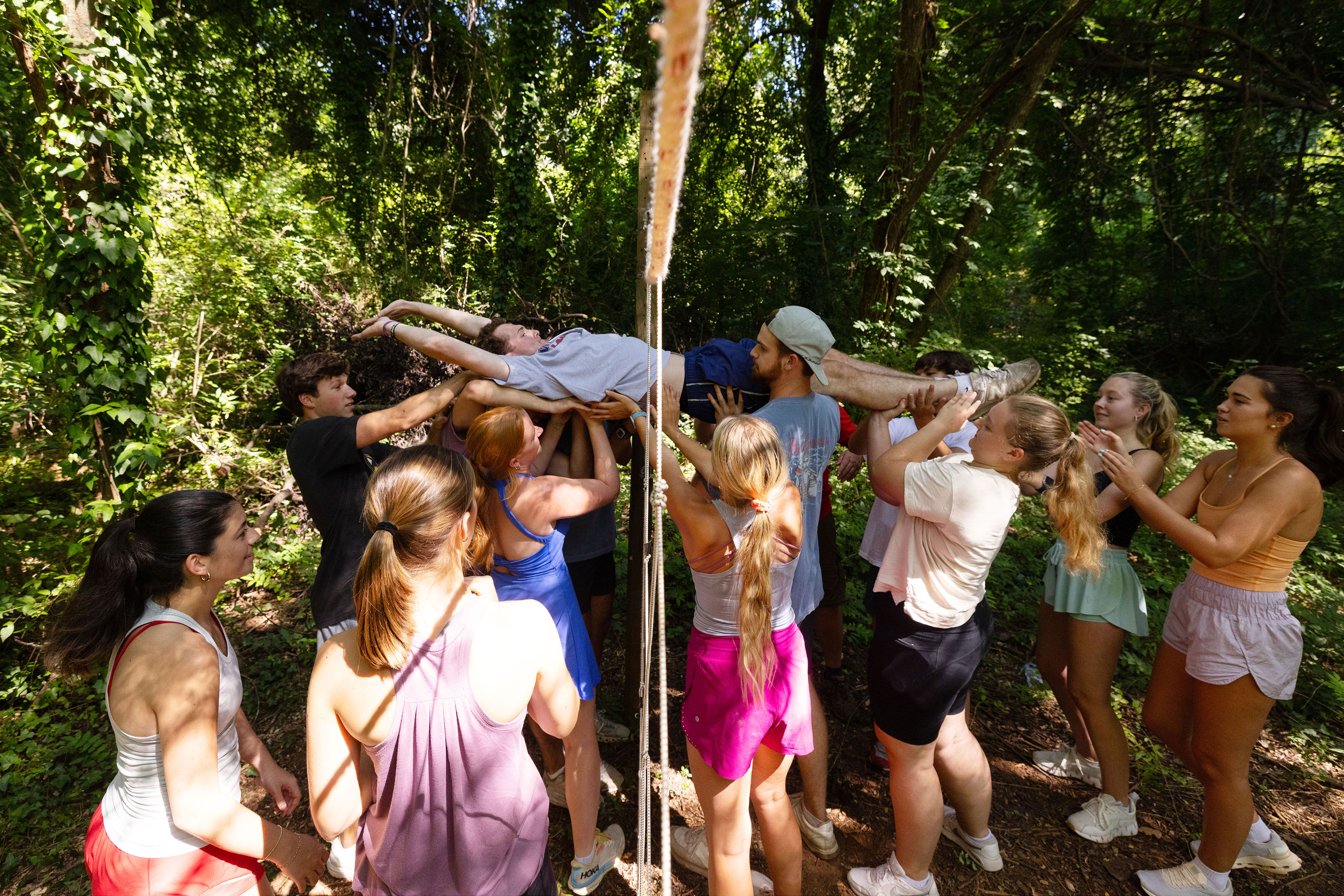 multiples students support the weight of a fellow student as they pass him through ropes during a teambuilding exercise
