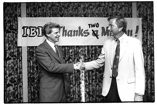 Two men shaking hands in front of a banner