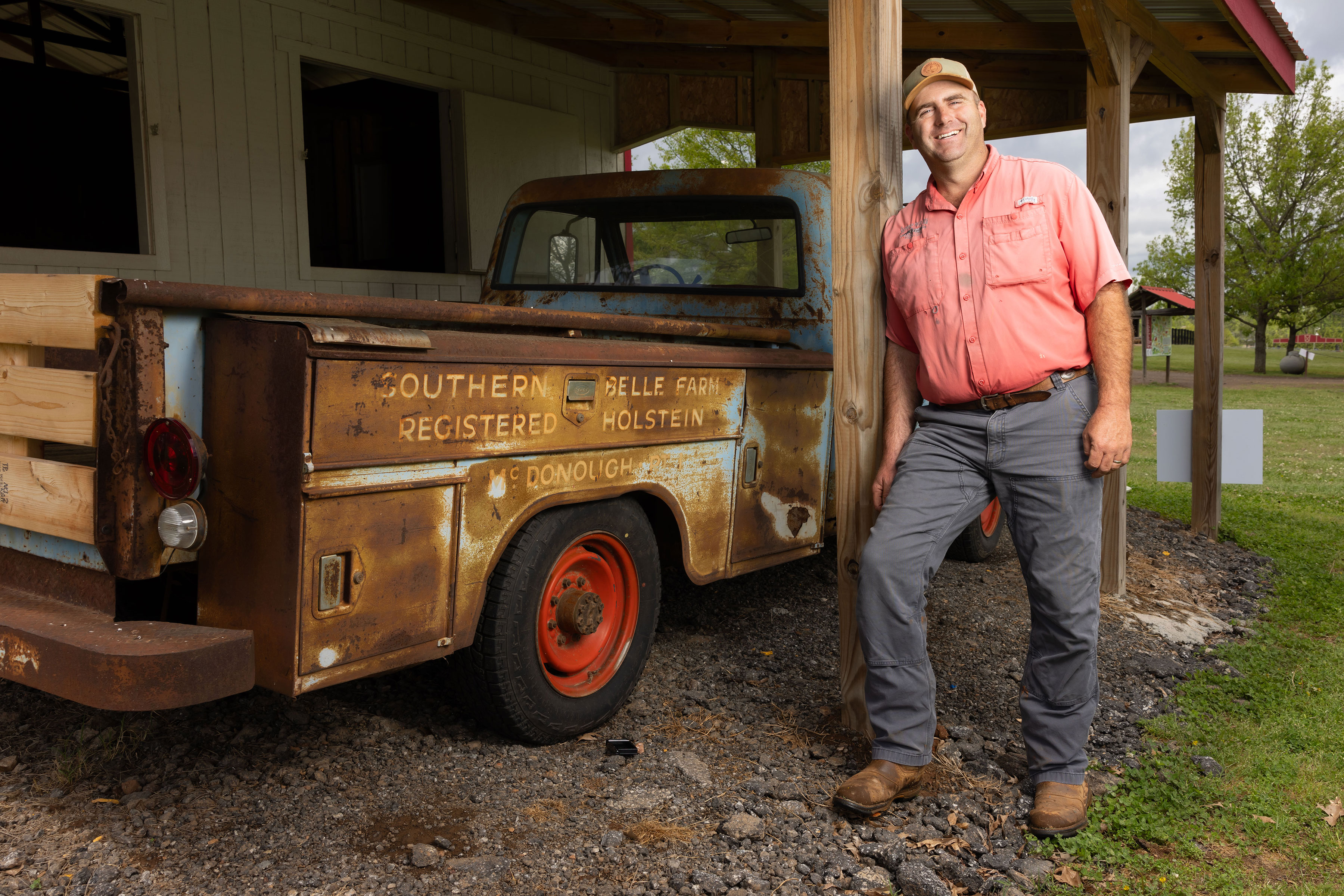 man poses next to vintage pickup truck
