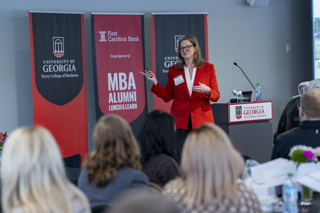 A woman in a red blazer giving a presentation