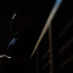 silhouette of male student holding phone