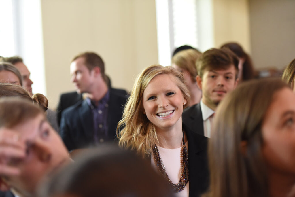 A female student smiles while talking with other students.
