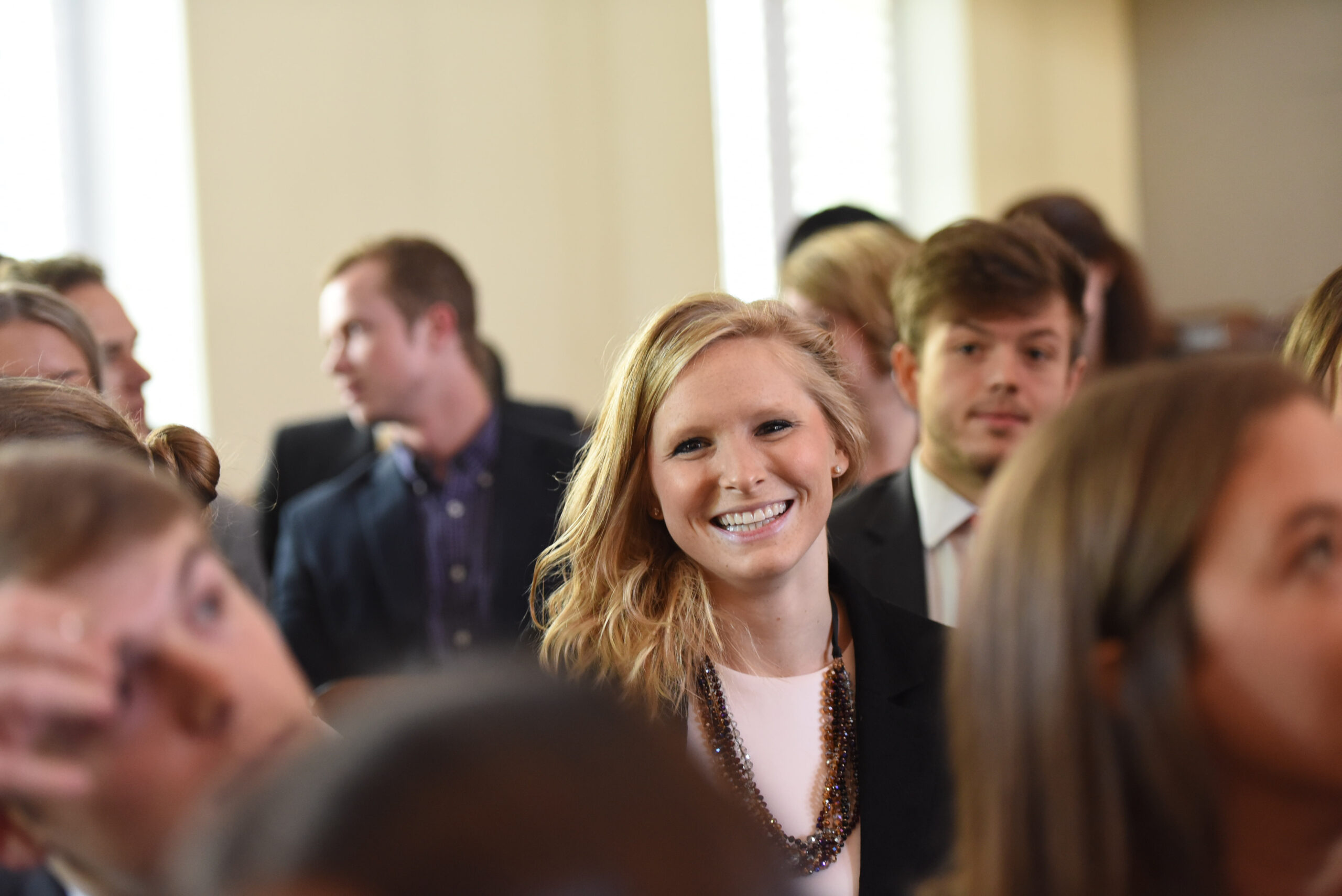 A female student smiles while talking with other students.