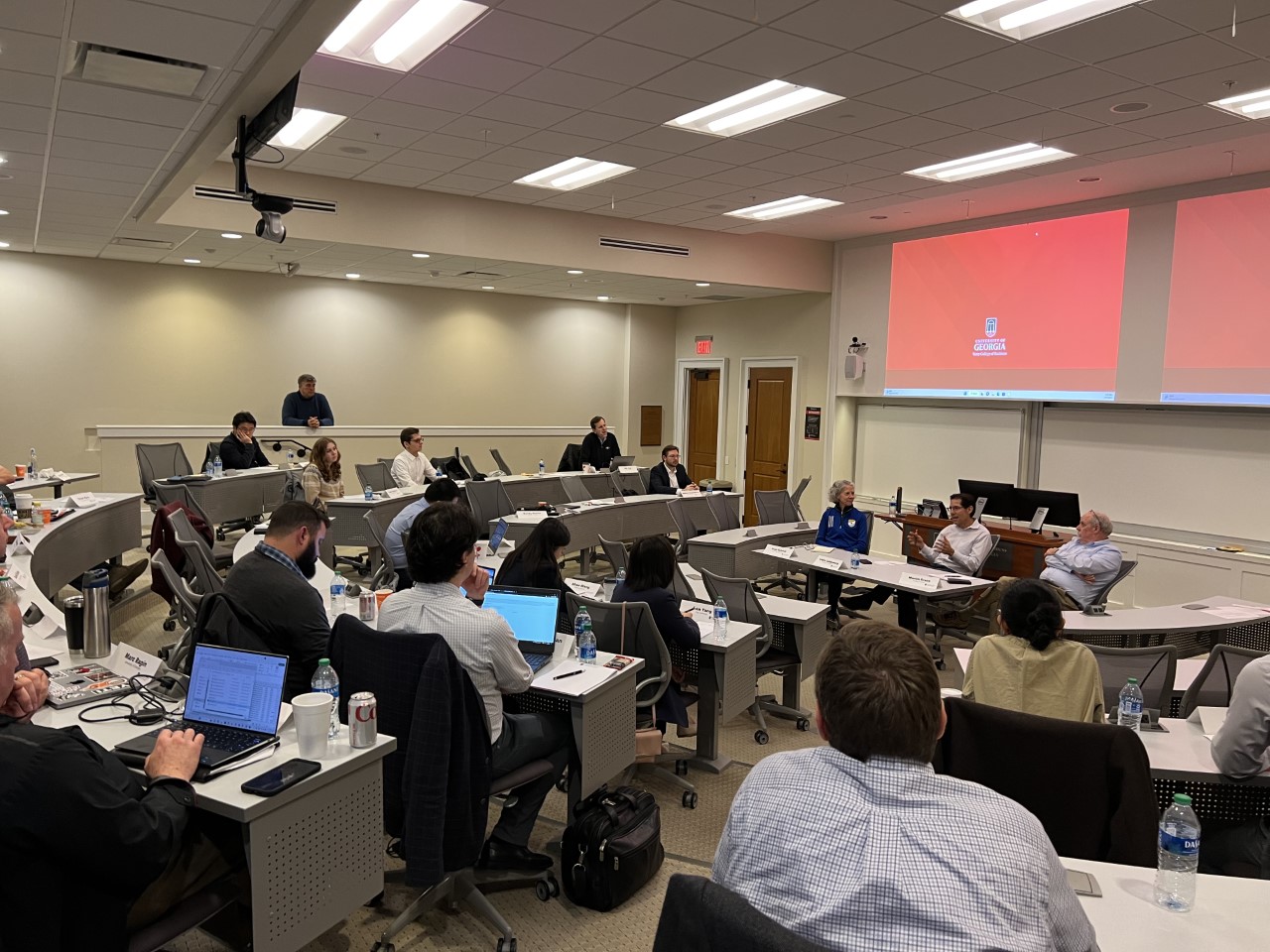 Participants in the Risk Management & Insurance Symposium listen to three speakers sitting in front of them in a BLC classroom.