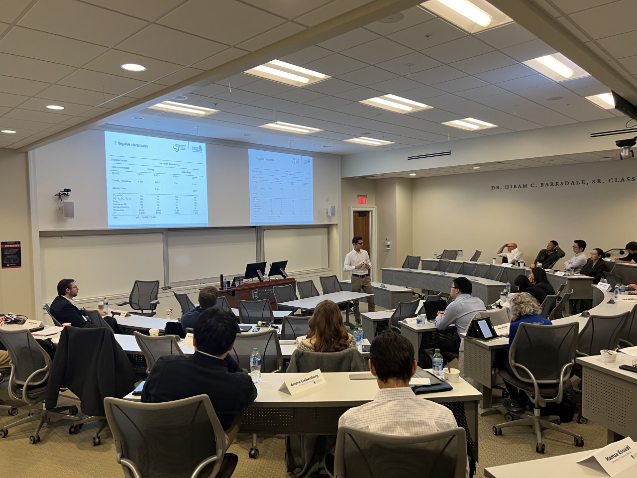 Participants in the Risk Management & Insurance Symposium listen to three speakers sitting in front of them in a BLC classroom.