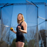 female athlete poses with hammer (track and field) behind neck and shoulders