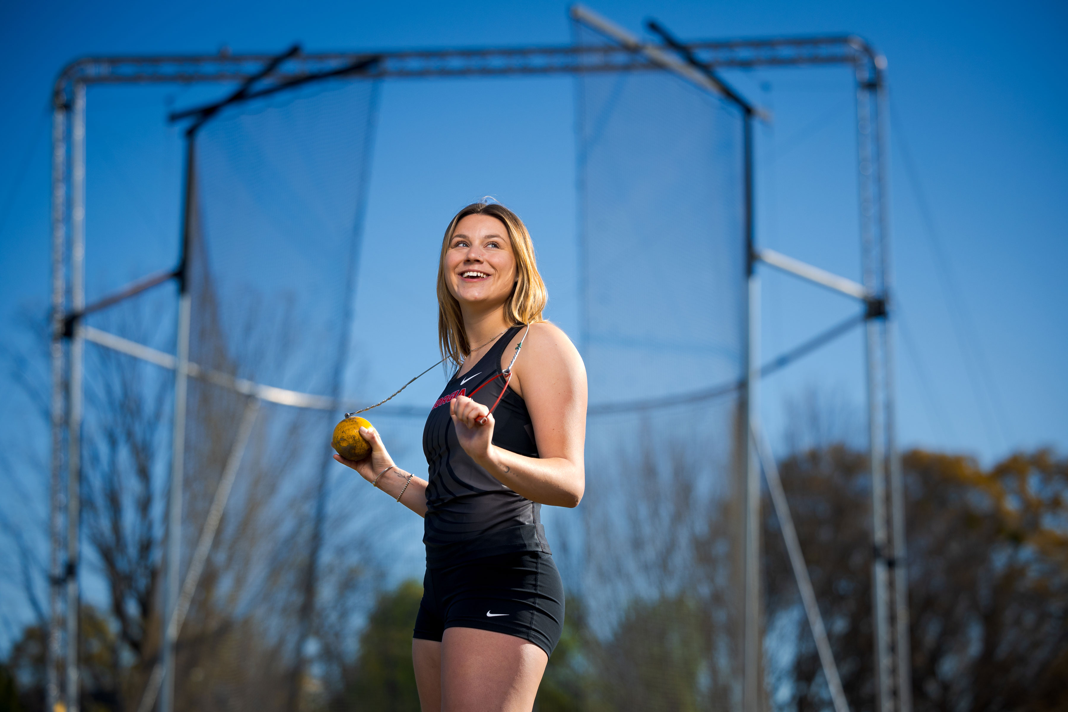 female athlete poses with hammer (track and field) behind neck and shoulders